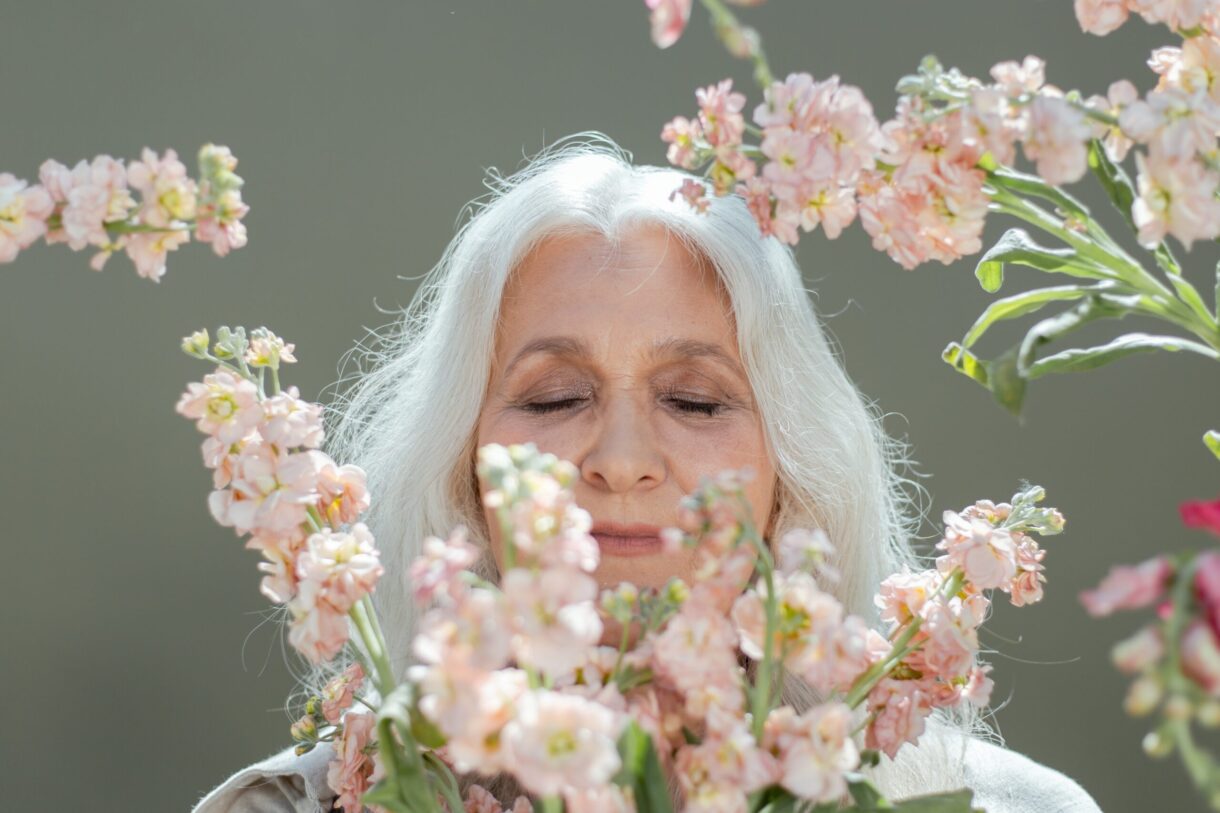 femme-agee-qui-pose-les-yeux-fermes-derriere-un-bouquet-de-fleurs